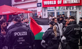 German police standing in front of protesters waving the Palestine flag